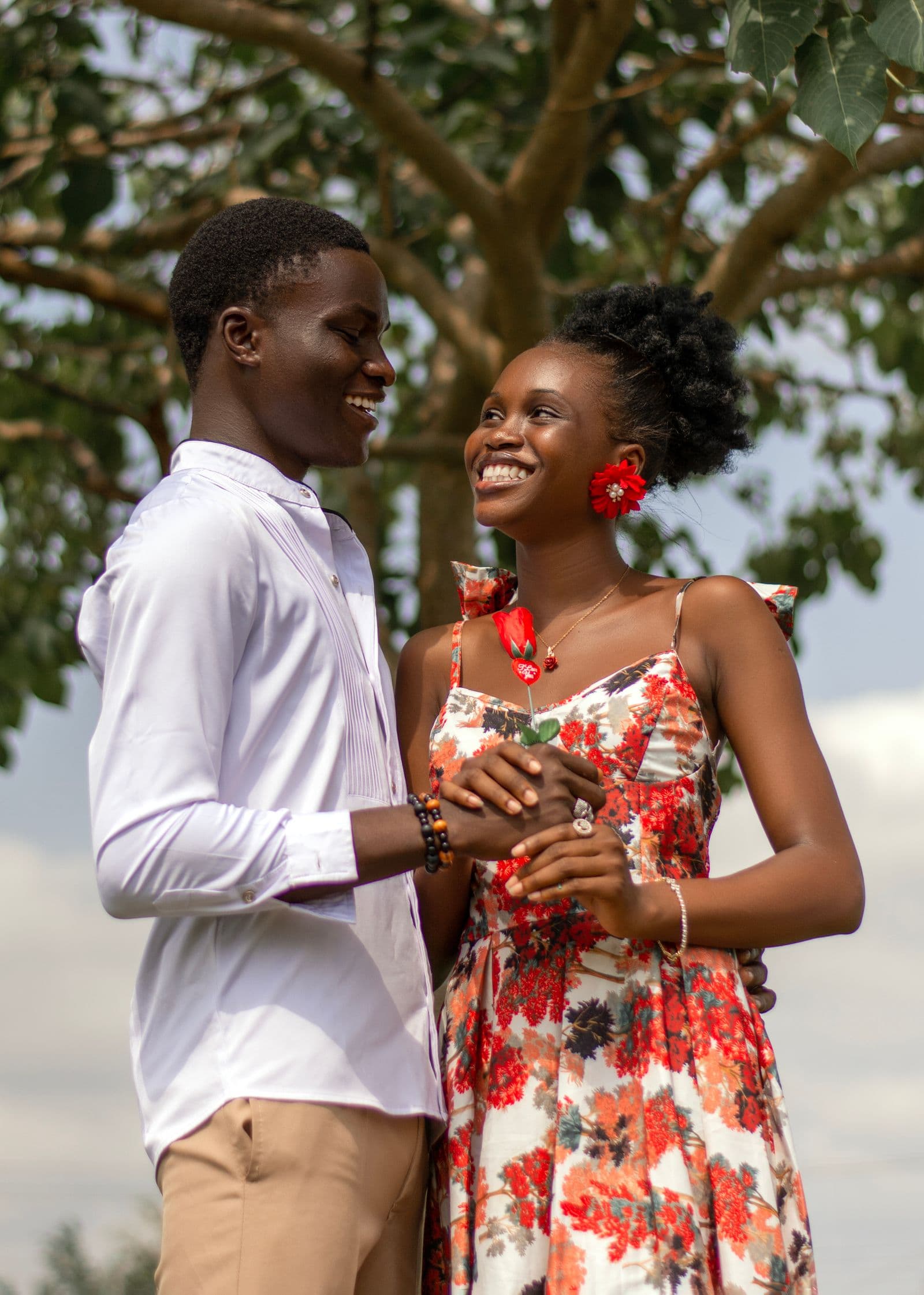 A joyful couple holding hands under a tree