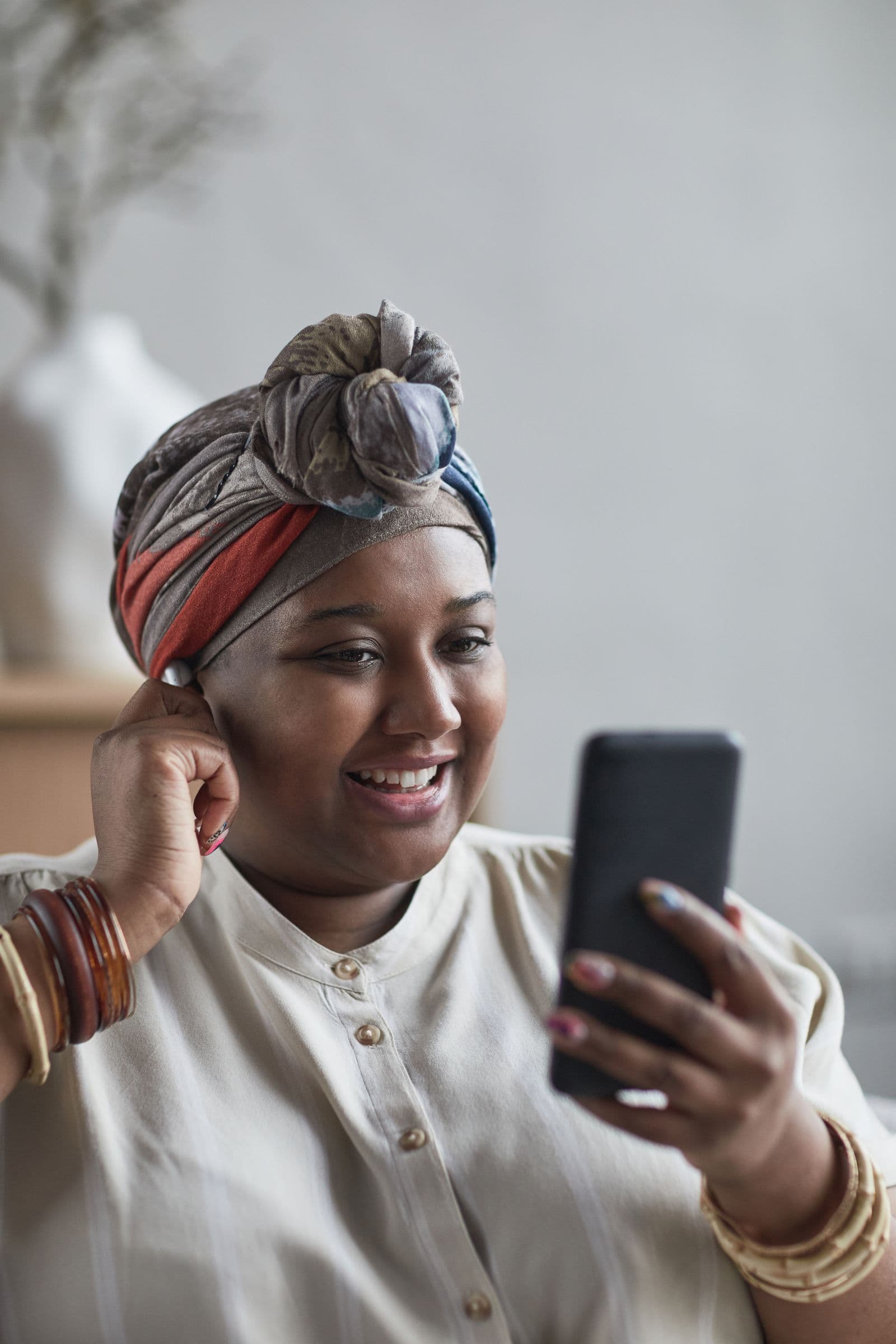 A woman in a headwrap smiling during a video call