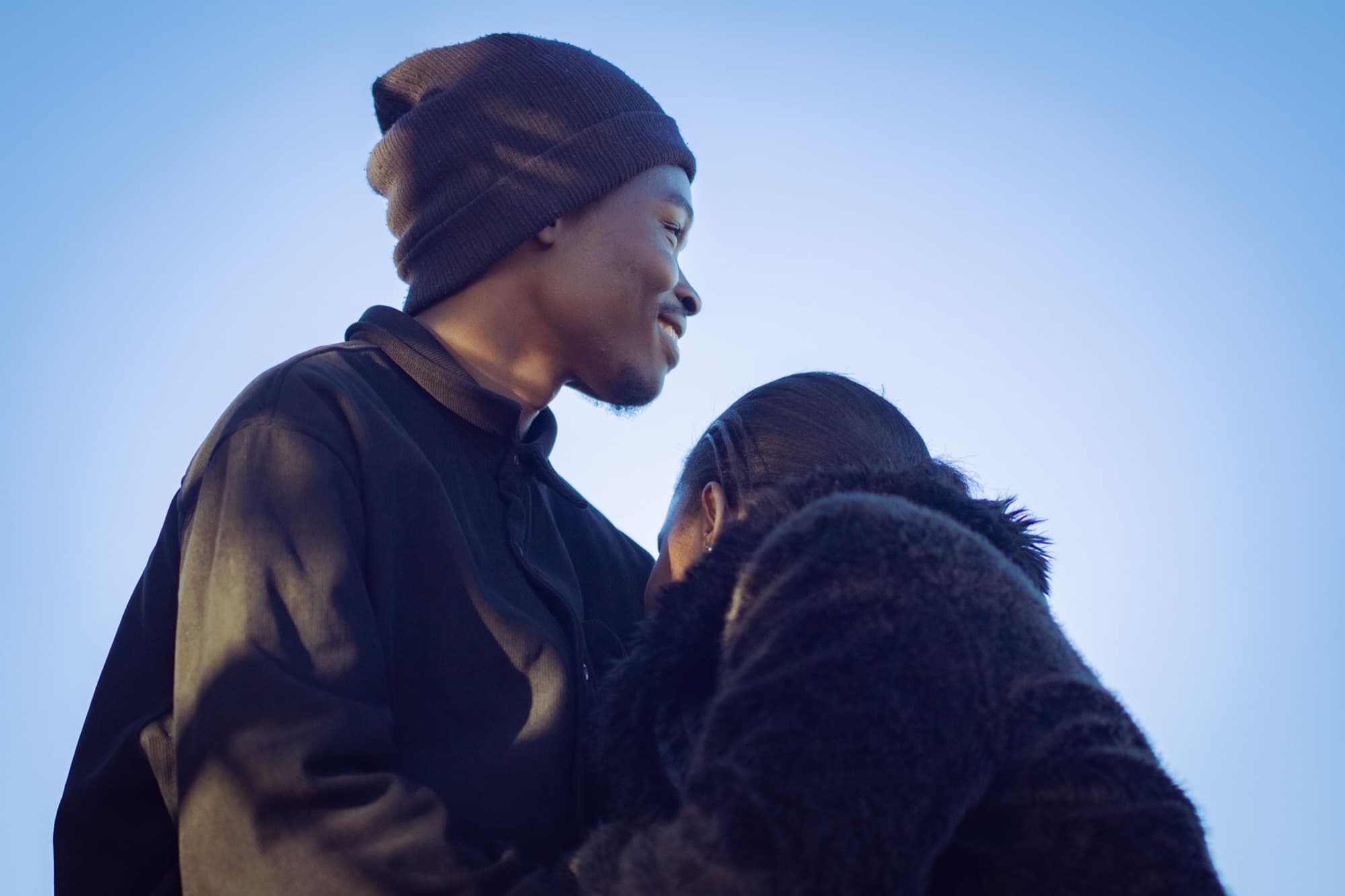 A young couple embracing under a clear sky