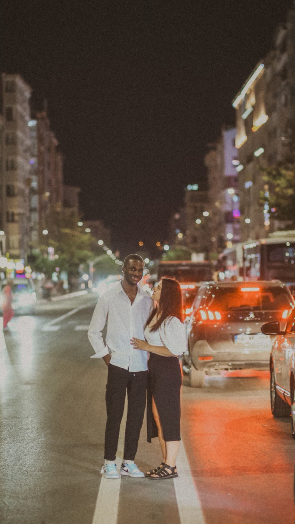 A couple standing close on a city street at night